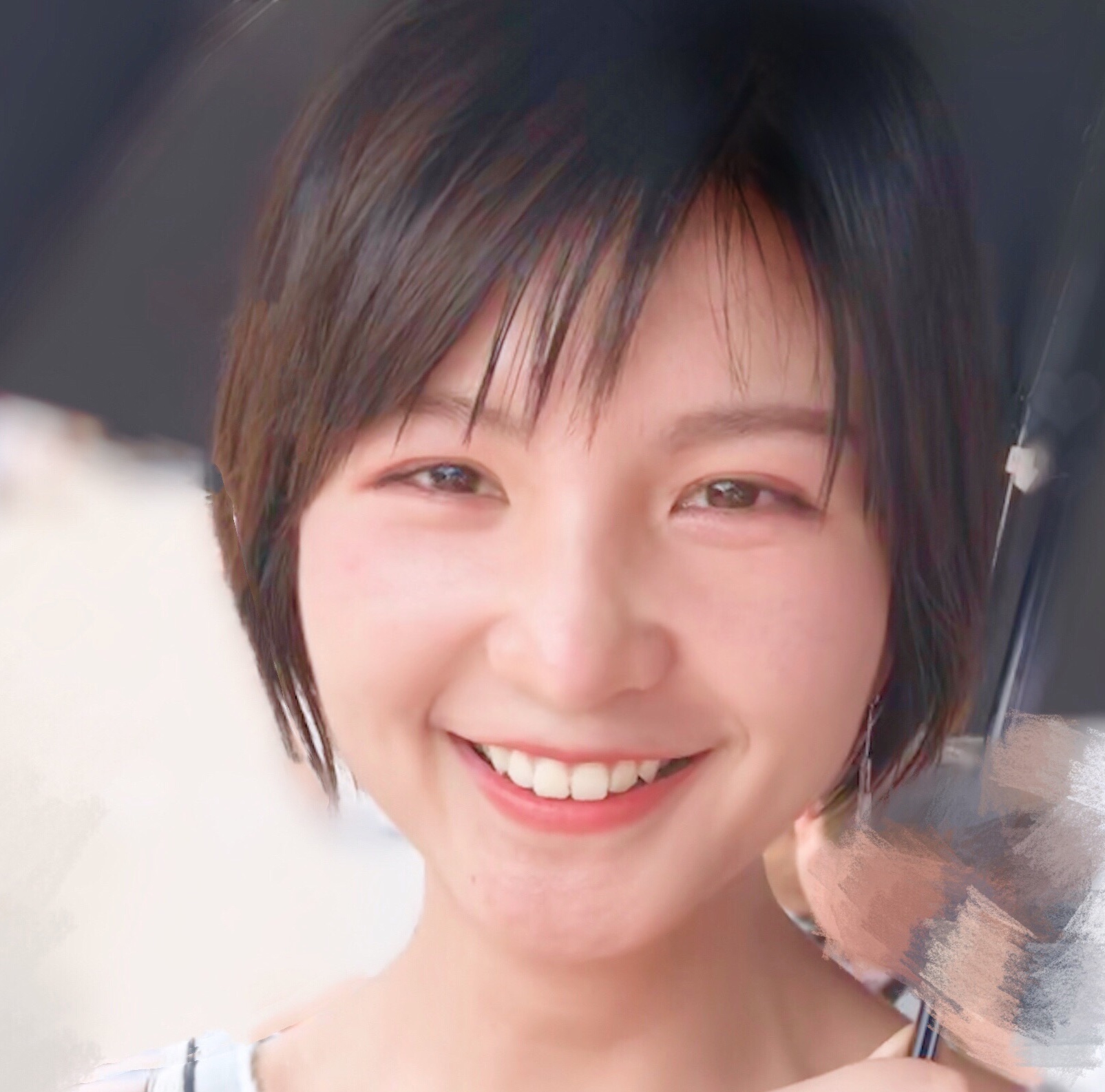 Close up portrait photo of a young female who appears to be Asian with short dark hair, fully smiling. She appears to be holding an umbrella.